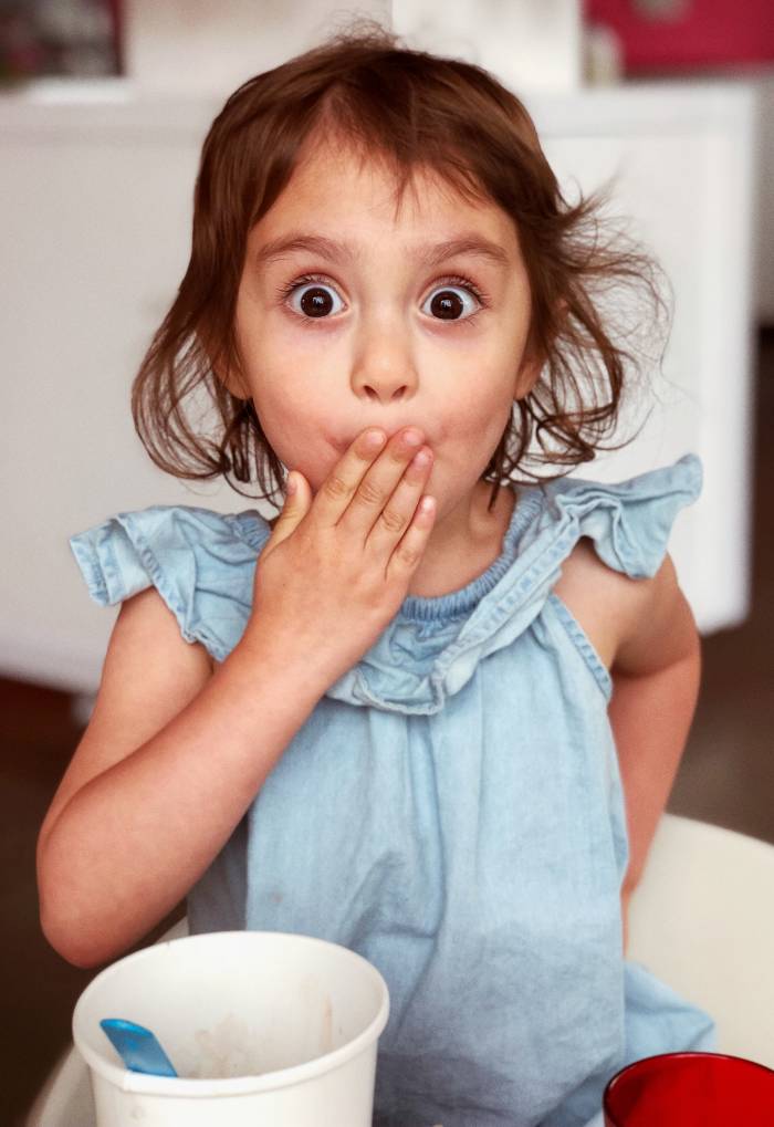 Petite fille avec la main devant la bouche